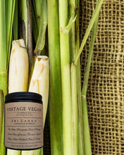 Load image into Gallery viewer, Sri Lanka Candle Lemongrass and Ginger soy wax candle with fresh lemongrass stalks on burlap background