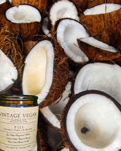 Load image into Gallery viewer, Fijian coconut vanilla and orange soy wax candle with tropical coconut halves background