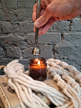 Load image into Gallery viewer, Luxury candle flame snuffer in stainless steel extinguishing a lit candle with wool decorations nearby