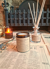 Load image into Gallery viewer, Cuban Oak and Tobacco Soy Wax Candle 180ml on vintage newspaper with reed diffuser and lit candle in cozy setting
