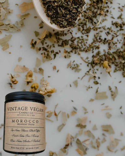 Moroccan Midnight Opium soy wax candle with vintage vegan label and natural dried herbs background
